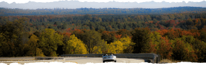 Sporty convertible with top down heads into a curve with a fall landscape in background