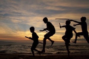 Kids with sticks at beach silhouetted against Michigan sunset