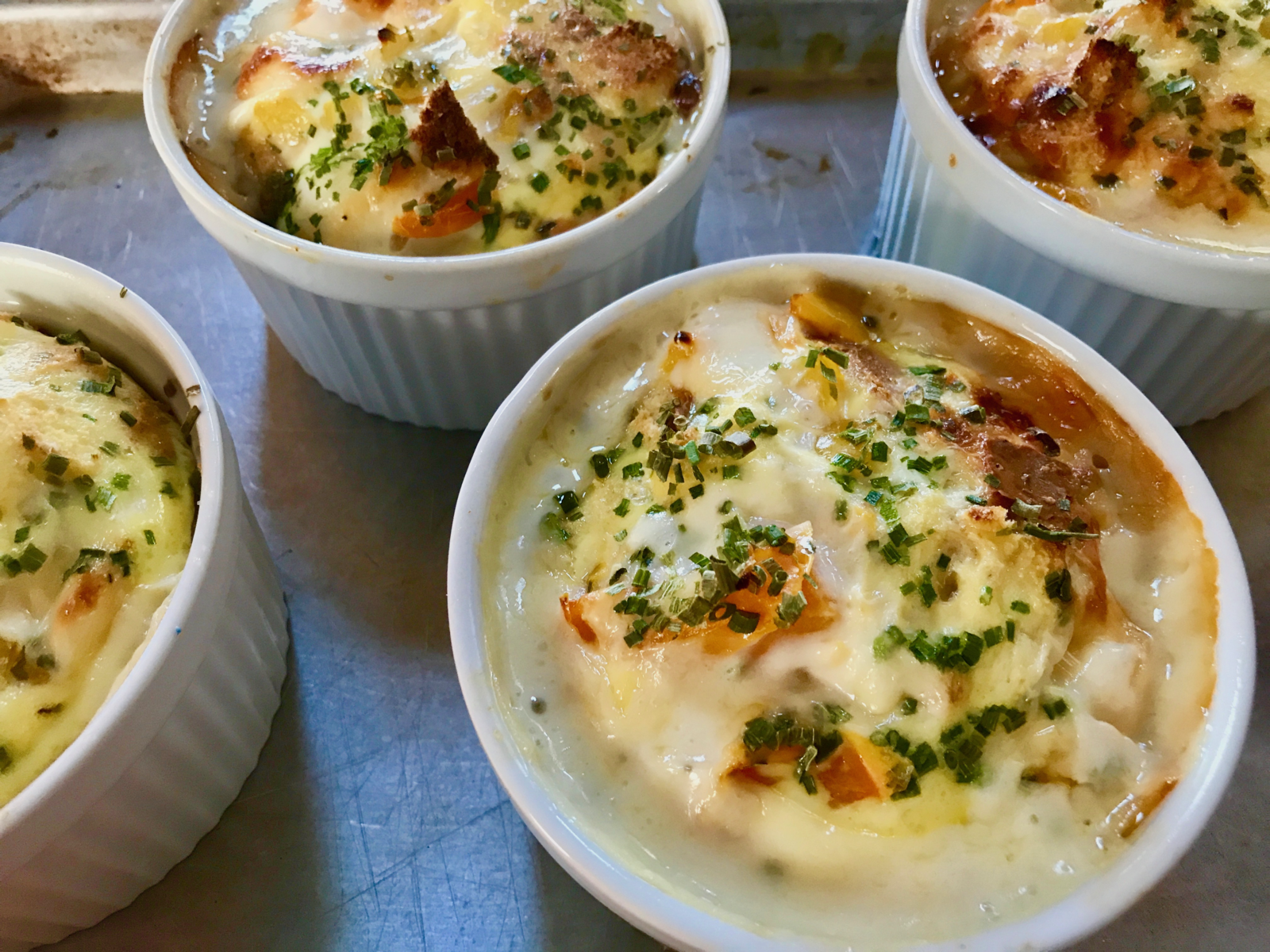 round dishes of baked eggs with browned cheese topping