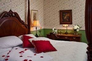 Room 5 at Kalamazoo house showing bed with red silky rose petals on it