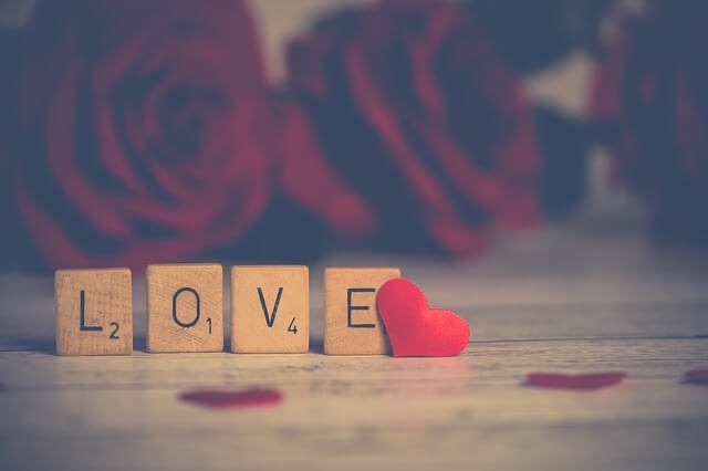 The word LOVE spelled out in letters of a Scrabble game with a red heart