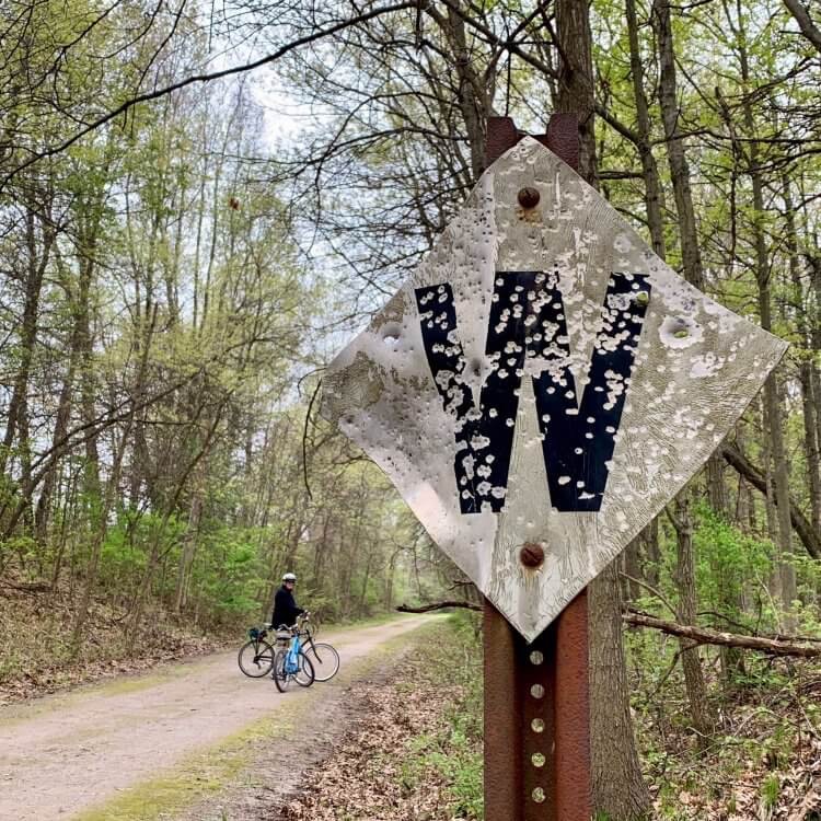 A diagonal sign alongside the Polly Ann Trail says only “W” and has numerous bullet holes