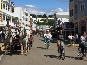 Horse-drawn wagon and bicycles share the road on Mackinac Island