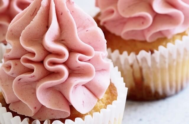 Swirls of pink icing top two muffins