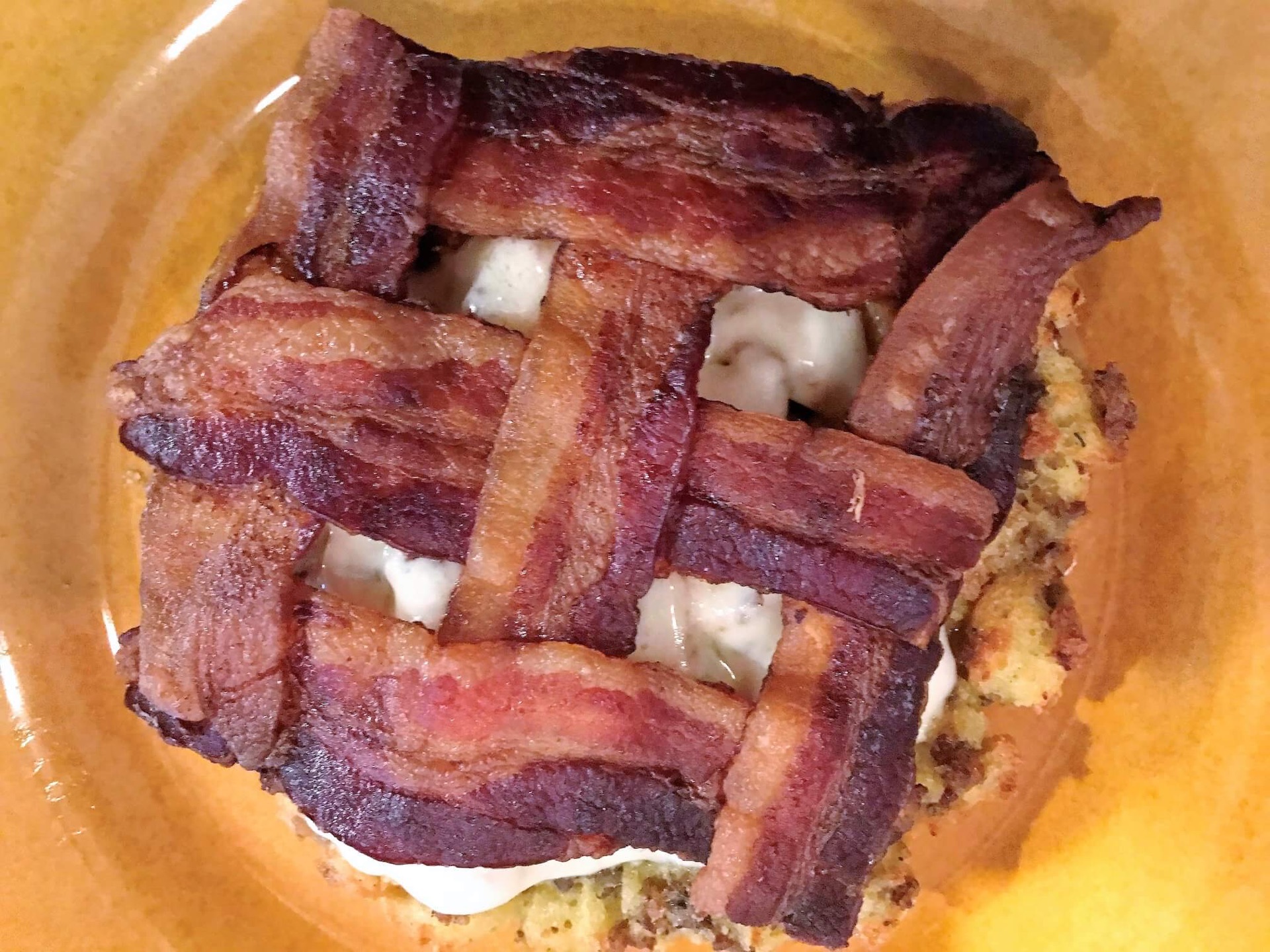 Crispy bacon in a basket-weave pattern atop a breakfast dish