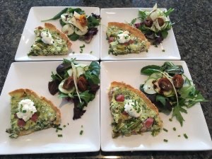 Four beautifully arranged plates of ham and asparagus quiche with an arugula and spinach salad.