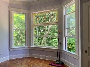 Bay window in a guest room overlooks trees in the side yard and shows renovated