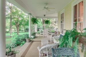 Long porch offers several seating choices overlooking landscaped yard.