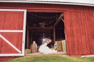 Bride and groom embrace inside the door of the red barn at the Farmhouse B&B