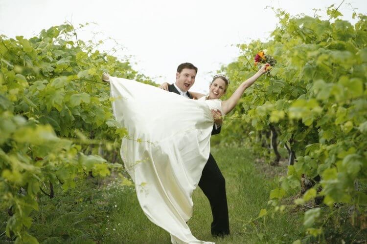 Groom lifts bride in triumph amid the vines at Chateau Chantal