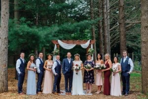Wedding party poses against a backdrop of tall trees and evergreens at Goldberry Woods