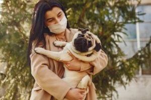 Woman wearing a mask cuddles her dog