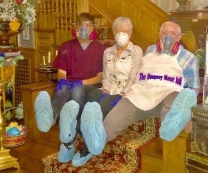 Three innkeepers at The Dempsey Manor Inn show off their masks and protective booties.