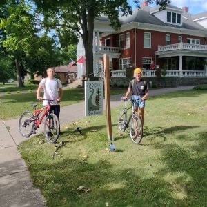 A man and woman stand with their bikes in front of The Nordic Pineapple B&B.