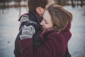 Young couple embrace outdoors in snow