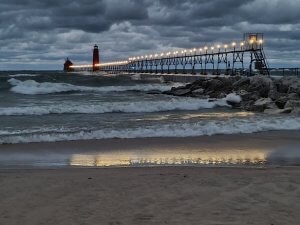 Grand Haven Inner and Outer Pier Lights with the white lights of the catwalk reflecting in the waves and pre-dawn storm clouds in background