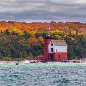 Round Island Lighthouse with fall-colored trees on Bois Blanc Island in background