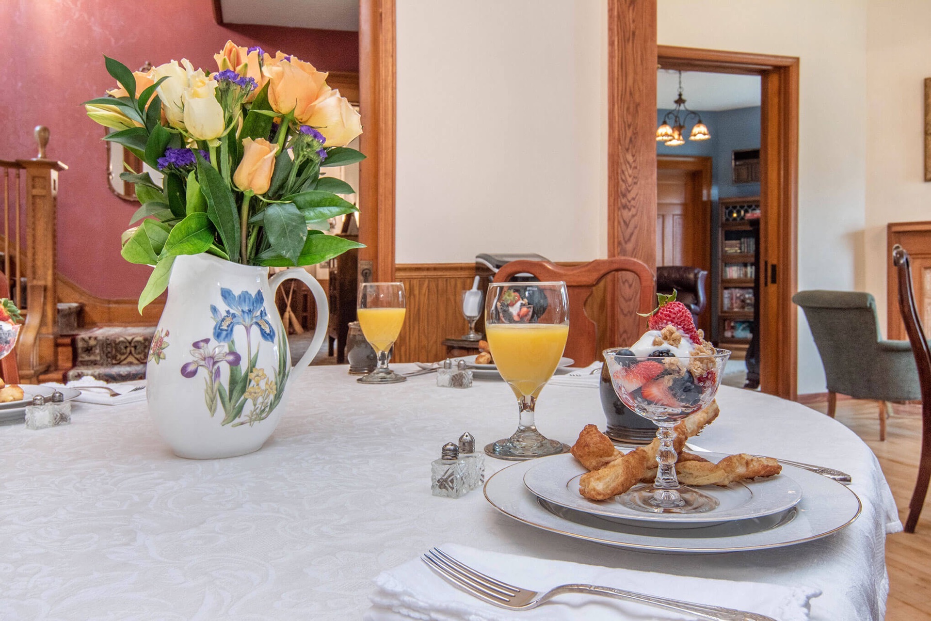 Breakfast table at Lamplighter B&B of Ludington is set with a vase of flowers, fruit course and orange juice