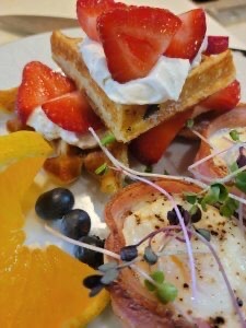 Strawberry shortcake waffles plus bacon-wrapped eggs topped with micro greens
