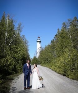 Bride and groom walking with New Presque Isle Lighthouse in the background