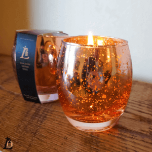 In a glass container, candles made for Lamplighter B&B.