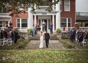 Bride and groom walk toward officiant standing on porch at Nordic Pineapple B&B