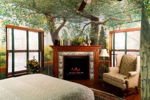 Sherwood Forest B&B guest room has a tree painted on the ceiling and a fireplace