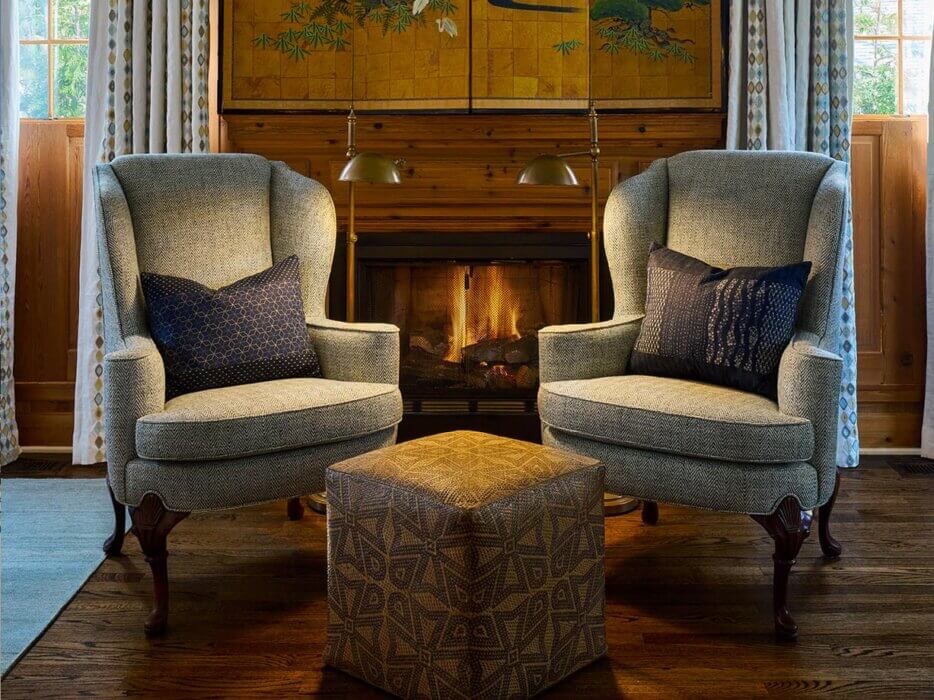 Two green chairs in front of a fireplace