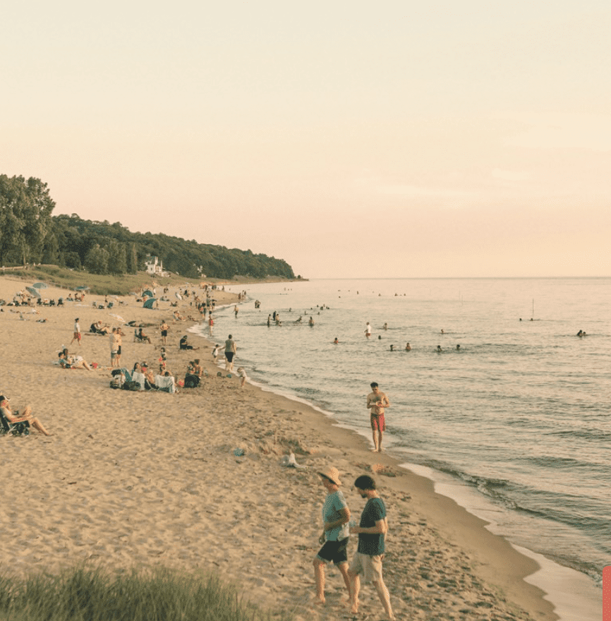 Saugatuck beach in the summer with people lounging in the sand and in the water