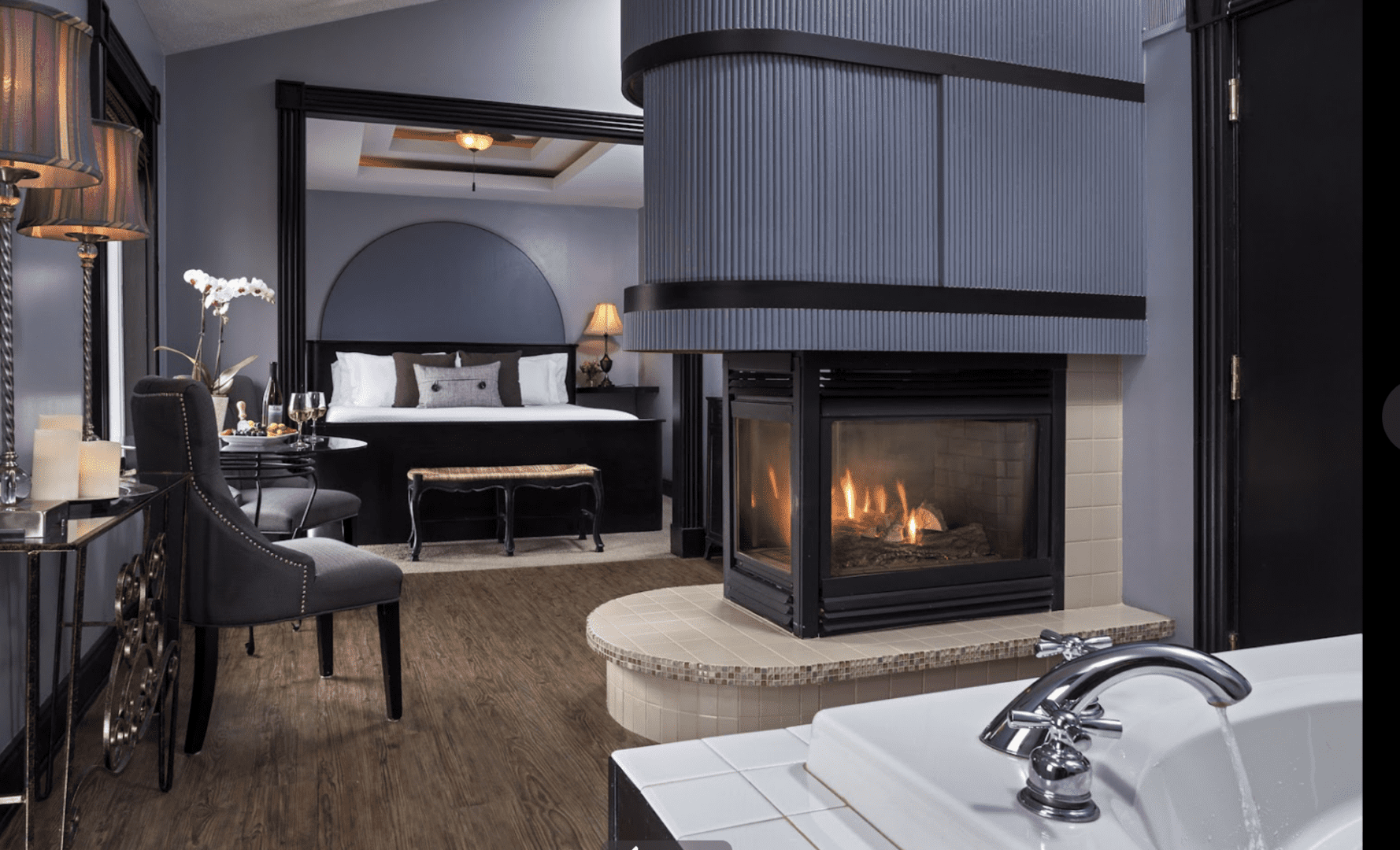 Elegant black bed with a fireplace and whirlpool tub. Lodging at the Castle in the Country