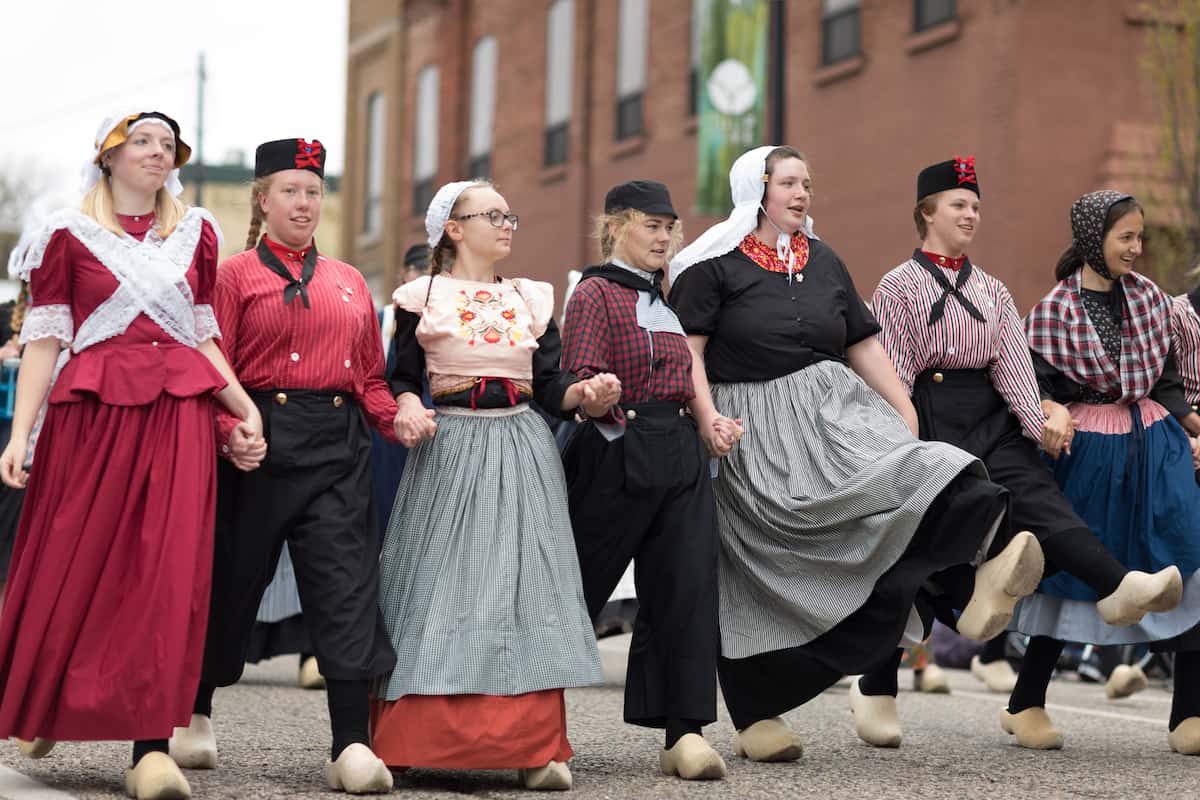 A group of young dutch women wearing traditional clothing perform a traditional dance at the Muziek Parade, during the Tulip Time Festival
