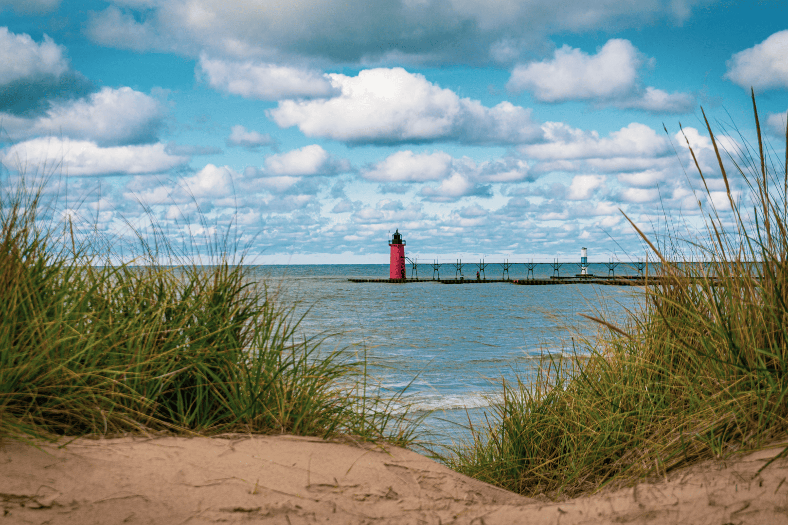 Distant views of South Haven LIghthouse with sandy beach and grasses