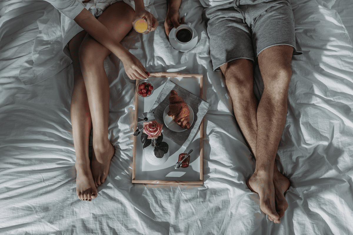 Couple having breakfast in bed with a tray in the middle