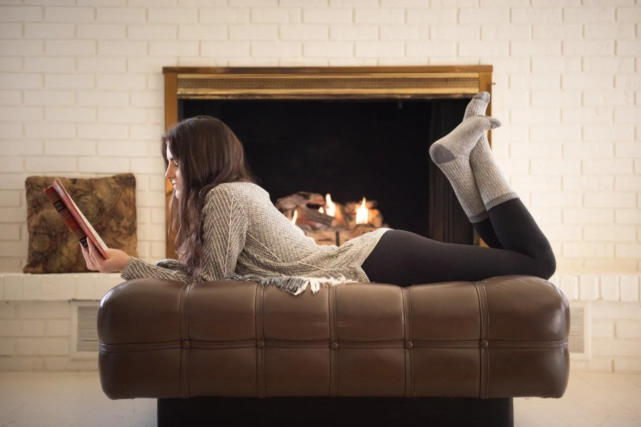 Girl on a sofa with her knees up in from of a fireplace