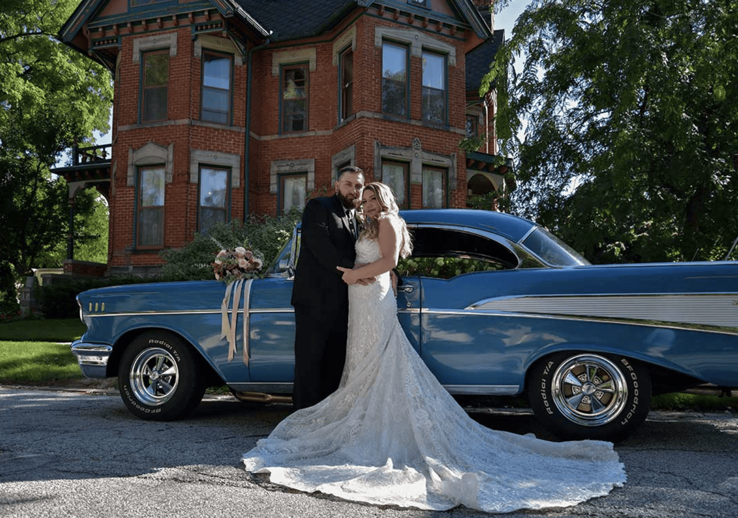 Bride and groom standing in front of a vintage blue car at the Historic Website House