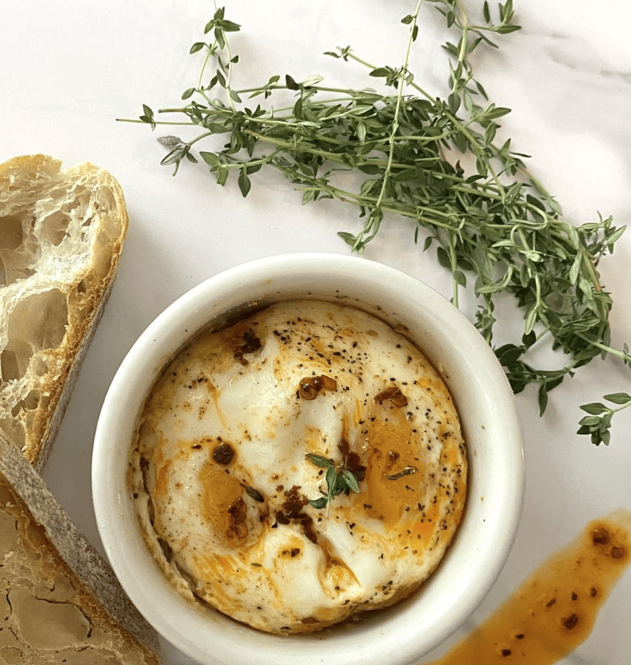 Breakfast soufflé in a white dish on a cutting board with fresh thyme
