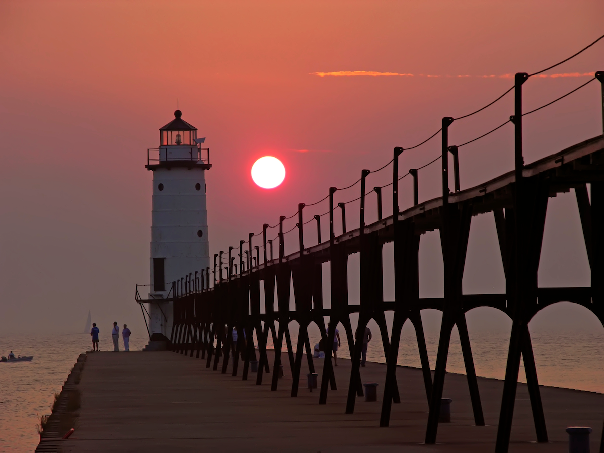 Several people beside the Manistee Lighthouse at sunset