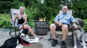 A couple sitting by a fire-it with their dogs