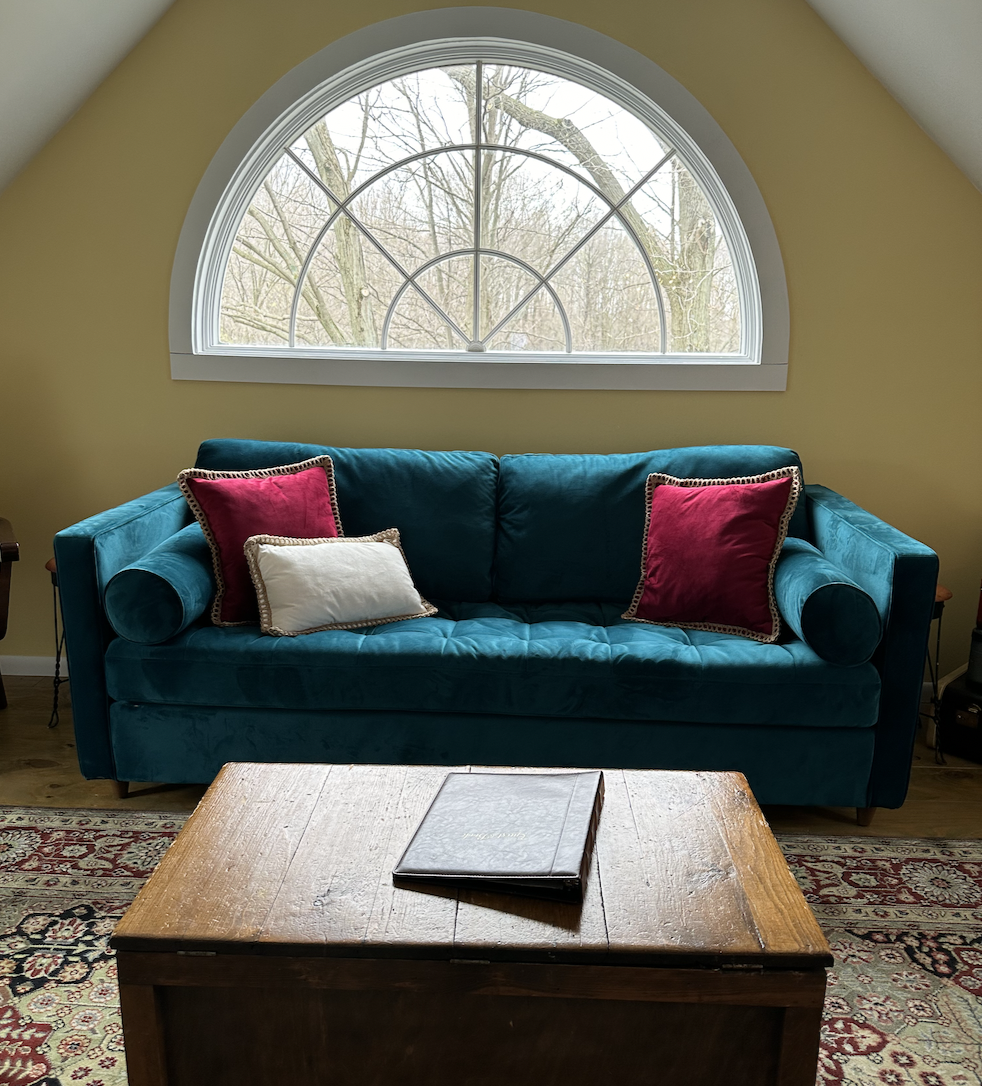 Emerald Blue Sofa with a half moon window behind at the Vintage Inn